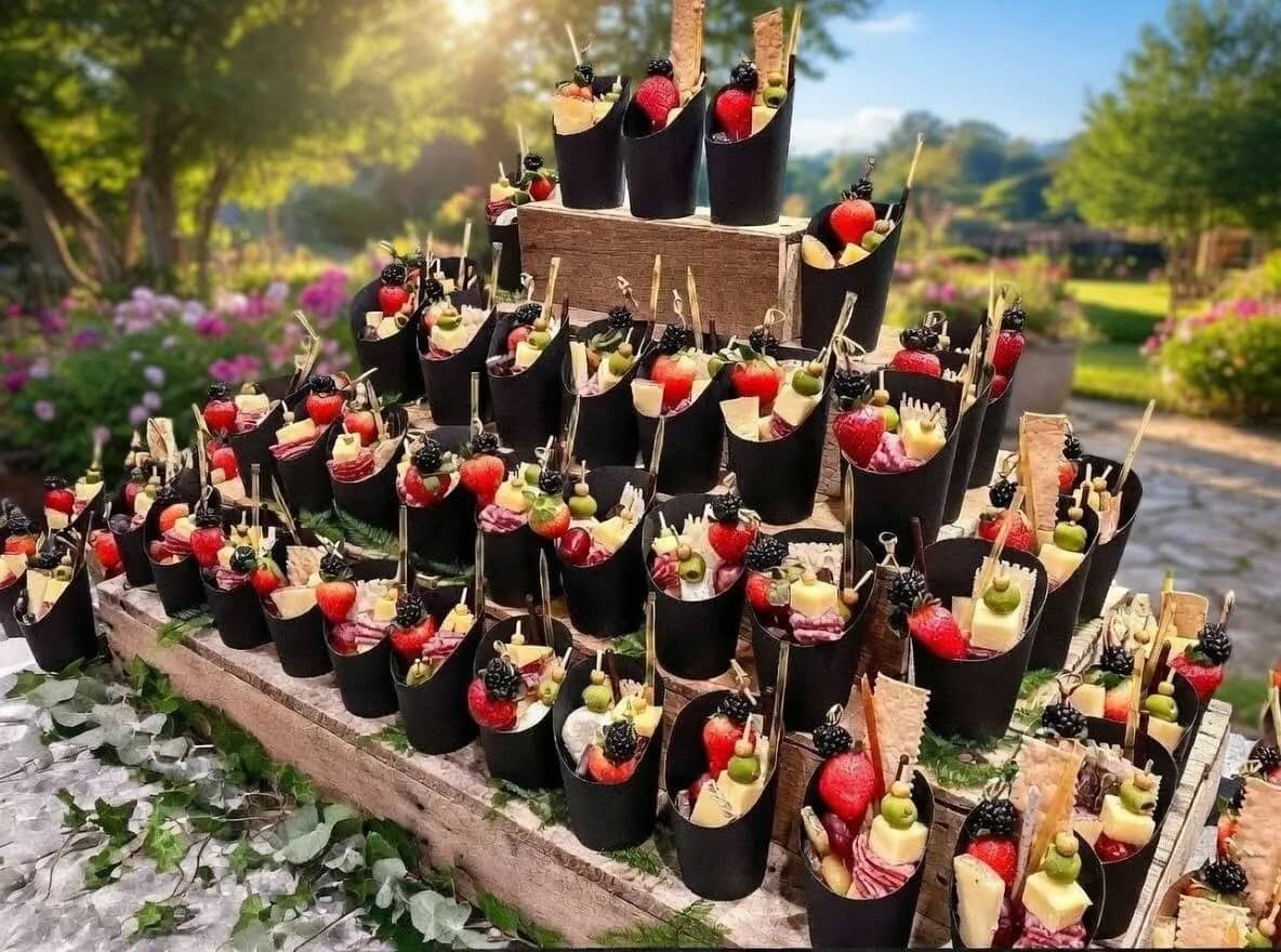 A display of The Cured Crow charcuterie cups arranged at an outdoor event