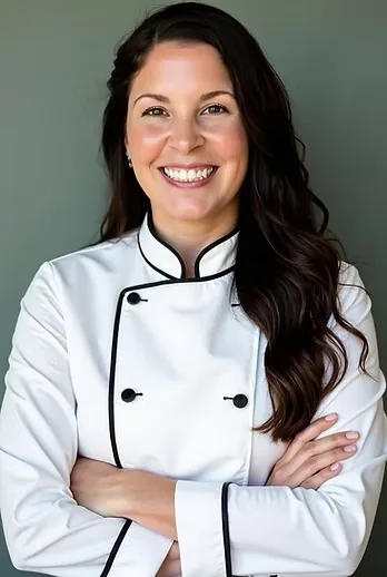 Tarin, owner of The Cured Crow, smiling in her chef's coat